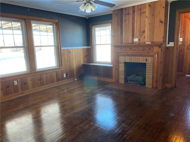 unfurnished living room featuring ceiling fan, dark hardwood / wood-style flooring, a brick fireplace, and crown molding