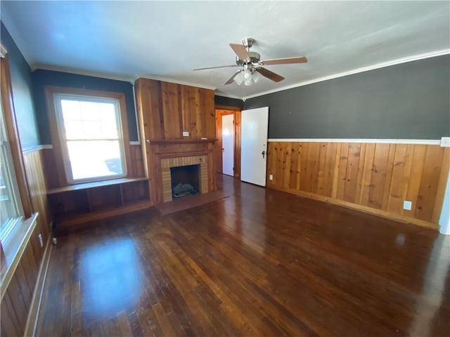 unfurnished living room featuring a fireplace, dark wood-type flooring, ceiling fan, and crown molding