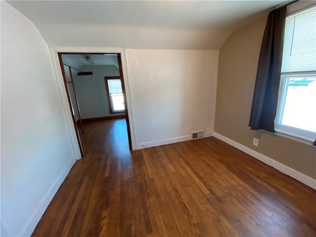 spare room featuring a healthy amount of sunlight, dark hardwood / wood-style flooring, and lofted ceiling