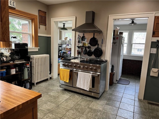 1007 10th St, Charleston, IL 61920 - kitchen featuring wall chimney range hood, radiator, range with two ovens, freestanding refrigerator, and ceiling fan