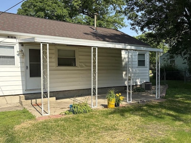 1216 Lawn Dr, Mattoon, IL 61938 - view of property exterior featuring a lawn, a patio area, and a shingled roof