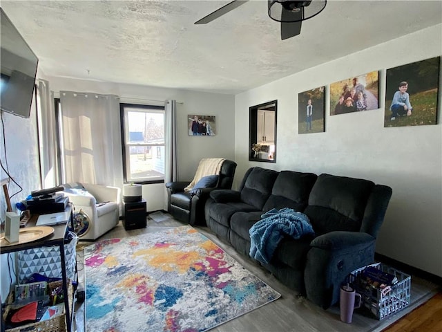 living room featuring ceiling fan, a textured ceiling, and wood finished floors