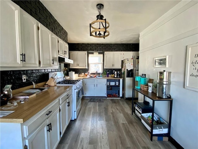 kitchen with white cabinetry, stainless steel fridge, under cabinet range hood, and white gas range