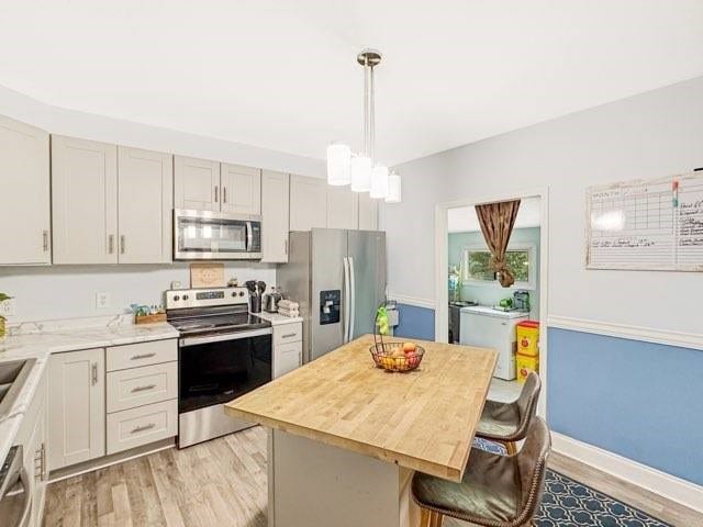 525 N 7th St, Charleston, IL 61920 - kitchen featuring stainless steel appliances, light wood-style flooring, a breakfast bar area, a center island, and hanging light fixtures