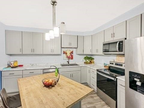 525 N 7th St, Charleston, IL 61920 - kitchen featuring appliances with stainless steel finishes, light wood finished floors, a kitchen island, pendant lighting, and gray cabinetry
