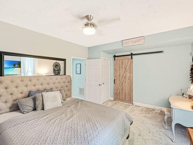 525 N 7th St, Charleston, IL 61920 - bedroom featuring a barn door, ceiling fan, and light carpet