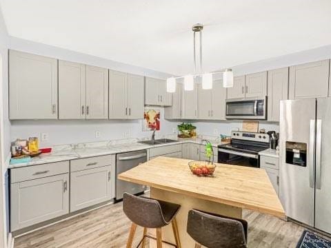 525 N 7th St, Charleston, IL 61920 - kitchen featuring stainless steel appliances, a breakfast bar area, light wood finished floors, gray cabinets, and pendant lighting