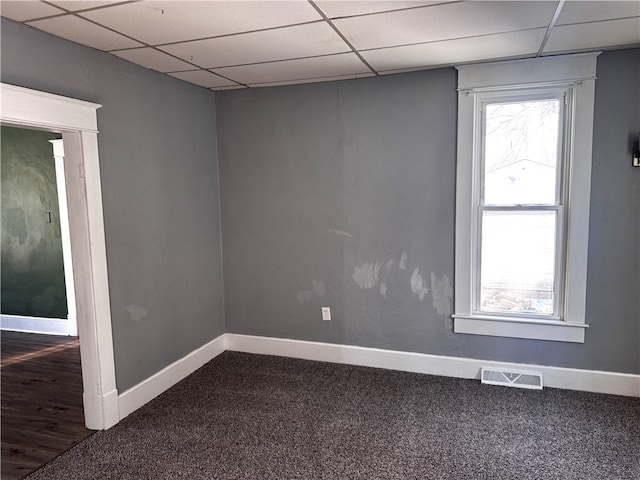 carpeted spare room with baseboards, visible vents, and a drop ceiling