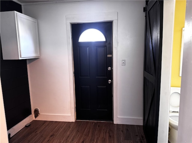 foyer entrance with dark wood-style floors, baseboards, and a barn door