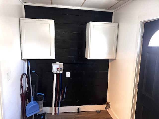 interior space featuring washer hookup, wood walls, wood finished floors, laundry area, and baseboards