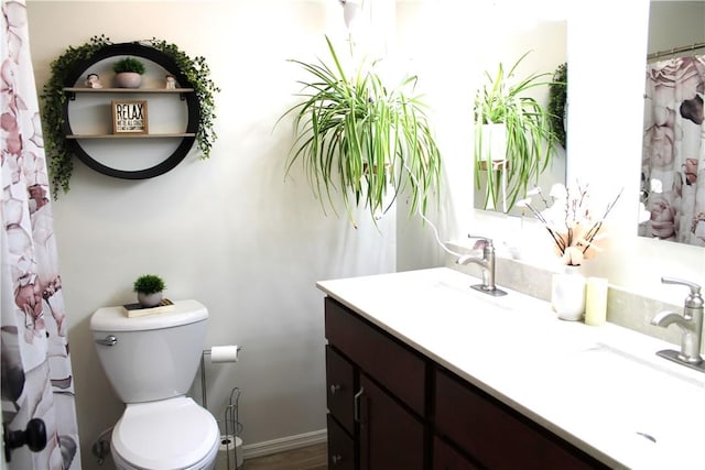 bathroom featuring toilet, vanity, and baseboards