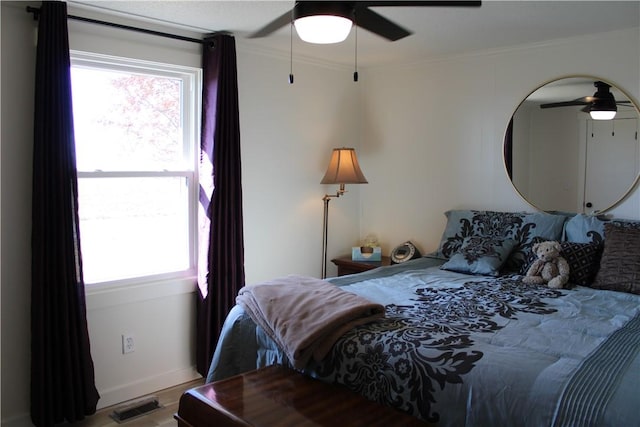 bedroom with visible vents, crown molding, a ceiling fan, and wood finished floors