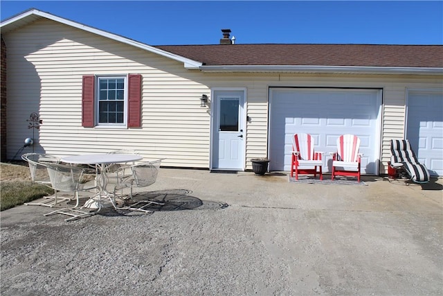 back of property featuring a patio, a garage, and roof with shingles