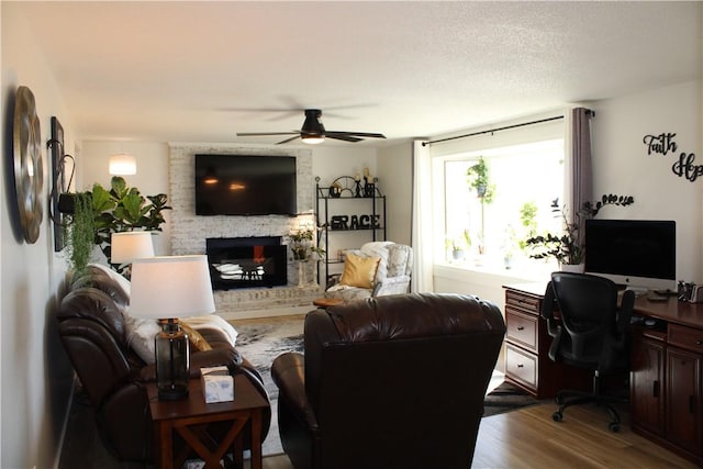 living room featuring a fireplace, a ceiling fan, and dark wood-style flooring