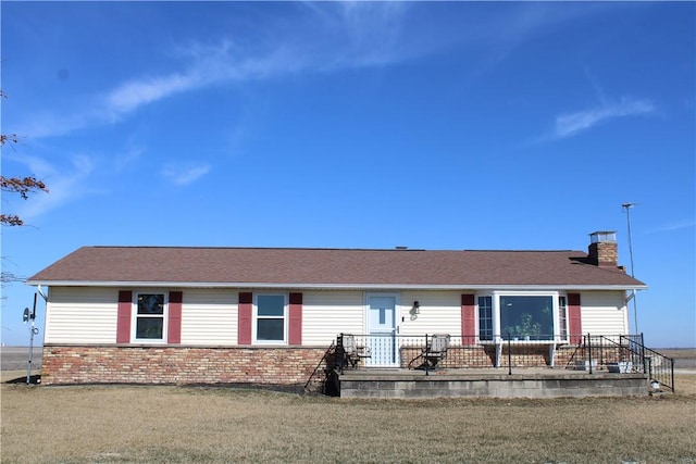 ranch-style home featuring a front lawn, brick siding, and a chimney