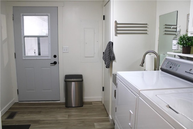 washroom with visible vents, washer and clothes dryer, electric panel, laundry area, and wood finished floors