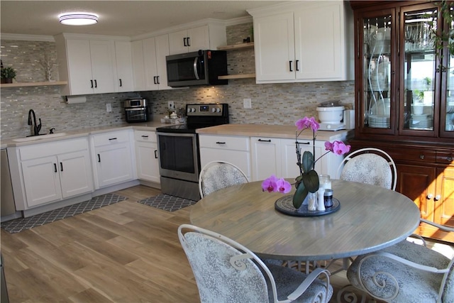 kitchen featuring a sink, appliances with stainless steel finishes, light countertops, and open shelves