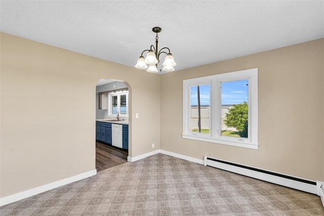 unfurnished dining area with dark colored carpet, a notable chandelier, a baseboard heating unit, and sink