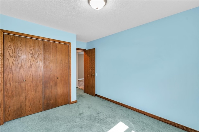 unfurnished bedroom with a textured ceiling, light colored carpet, and a closet