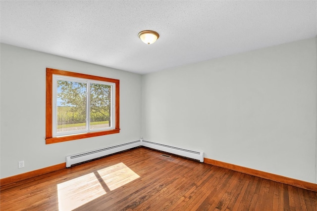 unfurnished room featuring hardwood / wood-style floors, a textured ceiling, and a baseboard heating unit