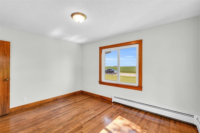 empty room with baseboard heating, light hardwood / wood-style flooring, and a textured ceiling