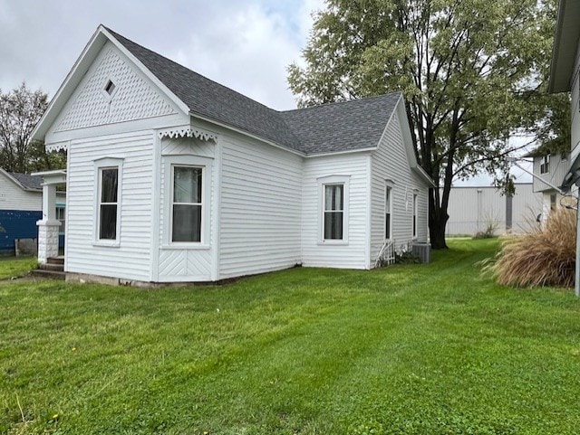 rear view of property featuring a lawn and roof with shingles