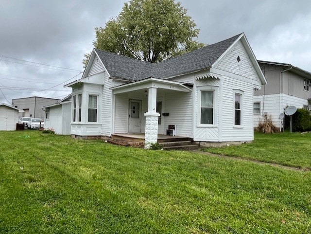 view of front of house with a front lawn, covered porch, and roof with shingles