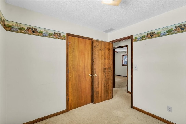 interior space featuring visible vents, baseboards, a textured ceiling, and light colored carpet