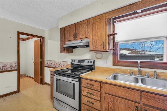 kitchen with under cabinet range hood, a sink, stainless steel range with electric cooktop, light countertops, and light floors