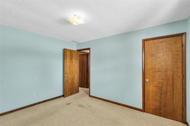 unfurnished room featuring baseboards, a textured ceiling, and light colored carpet