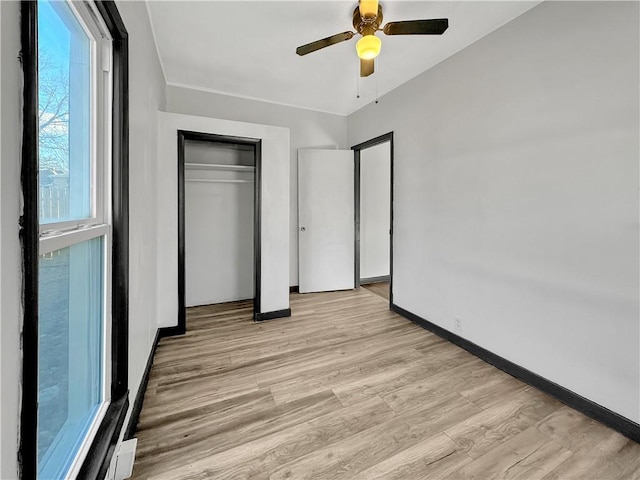 unfurnished bedroom with ceiling fan, light wood finished floors, a closet, and baseboards