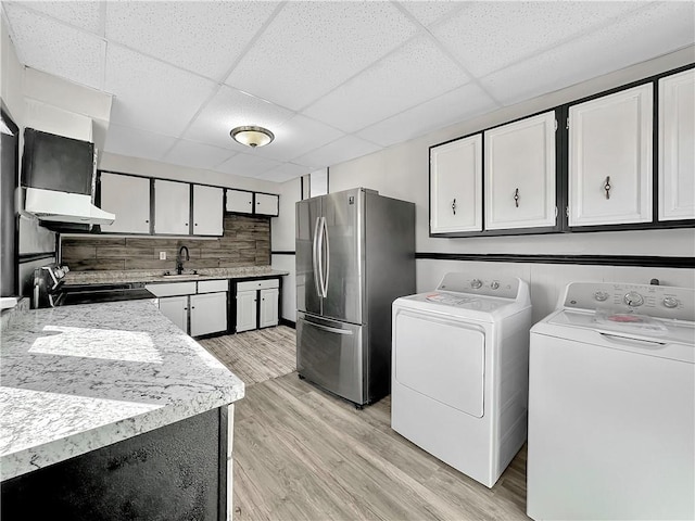 kitchen featuring washer and clothes dryer, stainless steel appliances, light countertops, white cabinetry, and light wood-type flooring