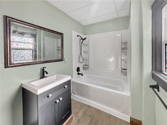full bath with bathtub / shower combination, a drop ceiling, wood finished floors, and vanity