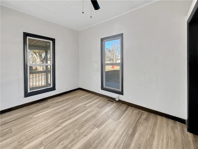 empty room with a ceiling fan, light wood-type flooring, visible vents, and baseboards