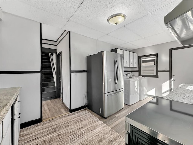 kitchen with light wood-style floors, freestanding refrigerator, a drop ceiling, and independent washer and dryer