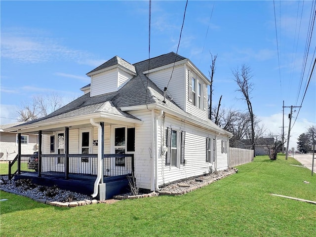 view of home's exterior featuring a shingled roof, a porch, and a lawn