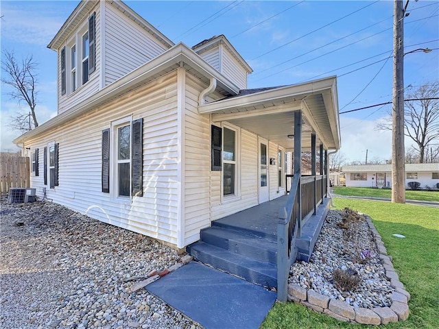 exterior space featuring covered porch, a yard, fence, and central air condition unit