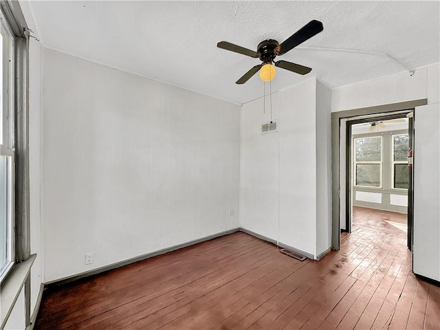 empty room featuring ceiling fan, hardwood / wood-style flooring, a textured ceiling, and visible vents