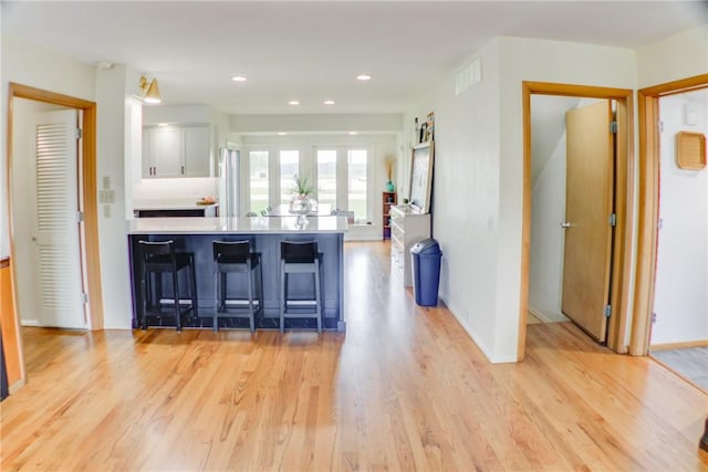 400 Country Club Rd, Mattoon, IL 61938 - kitchen with white cabinetry, a kitchen breakfast bar, light wood-style floors, a peninsula, and light countertops