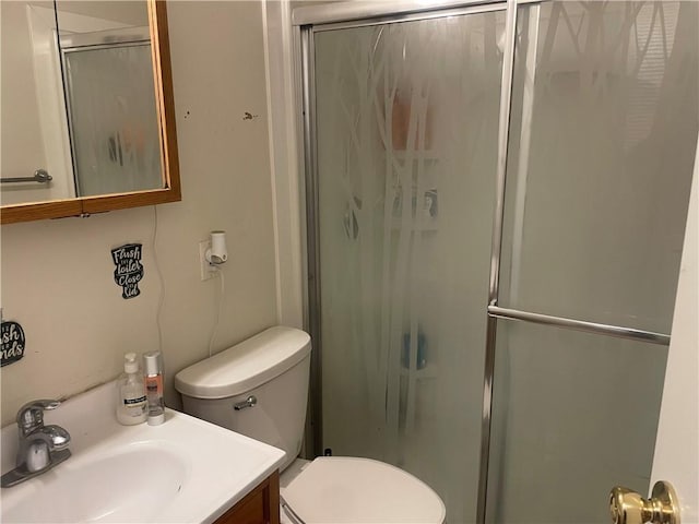 bathroom featuring vanity, toilet, and a shower with shower door