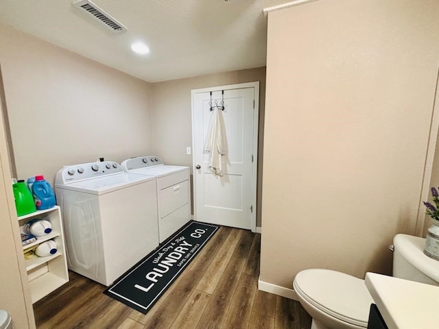 laundry room with laundry area, baseboards, visible vents, dark wood-style floors, and washing machine and clothes dryer