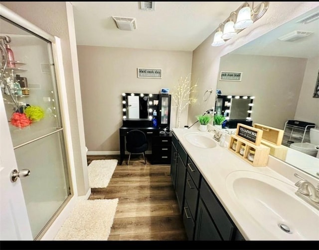 bathroom with a shower stall, visible vents, a sink, and wood finished floors