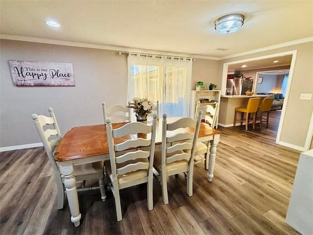 dining room featuring ornamental molding, wood finished floors, and baseboards