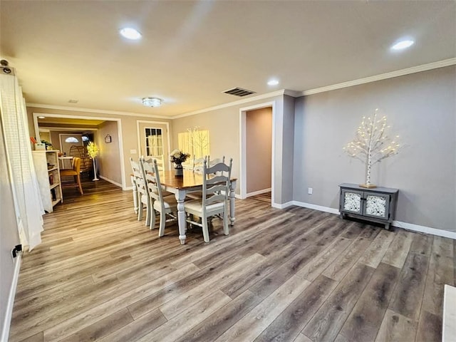 dining room with ornamental molding, visible vents, baseboards, and wood finished floors