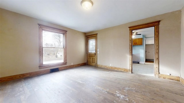 spare room with light wood-style flooring, visible vents, and baseboards