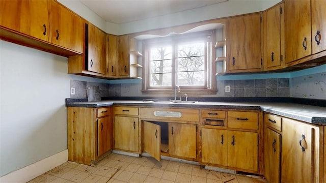 kitchen with dark countertops, tasteful backsplash, brown cabinets, and a sink