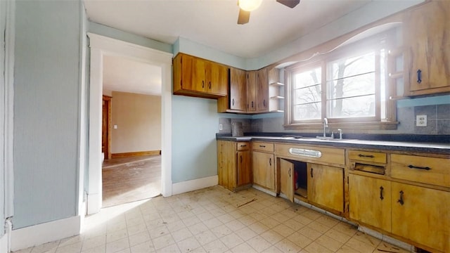 kitchen with brown cabinetry, dark countertops, a sink, and decorative backsplash