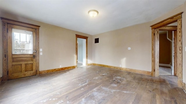 spare room featuring visible vents, baseboards, and wood finished floors