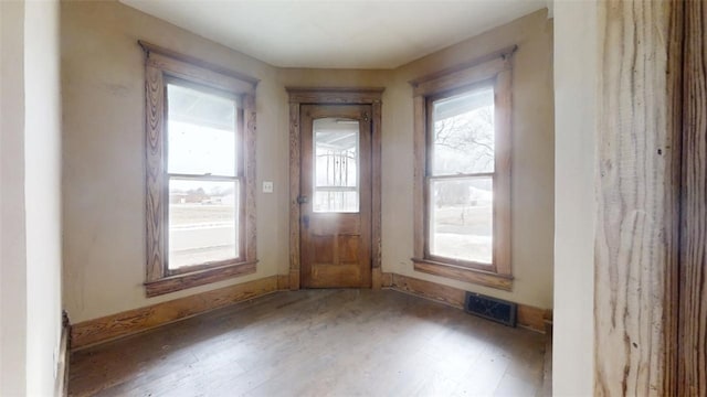 foyer with baseboards, visible vents, and wood finished floors