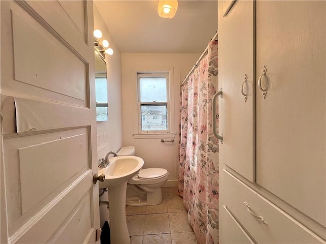 bathroom featuring toilet, baseboards, and tile patterned floors